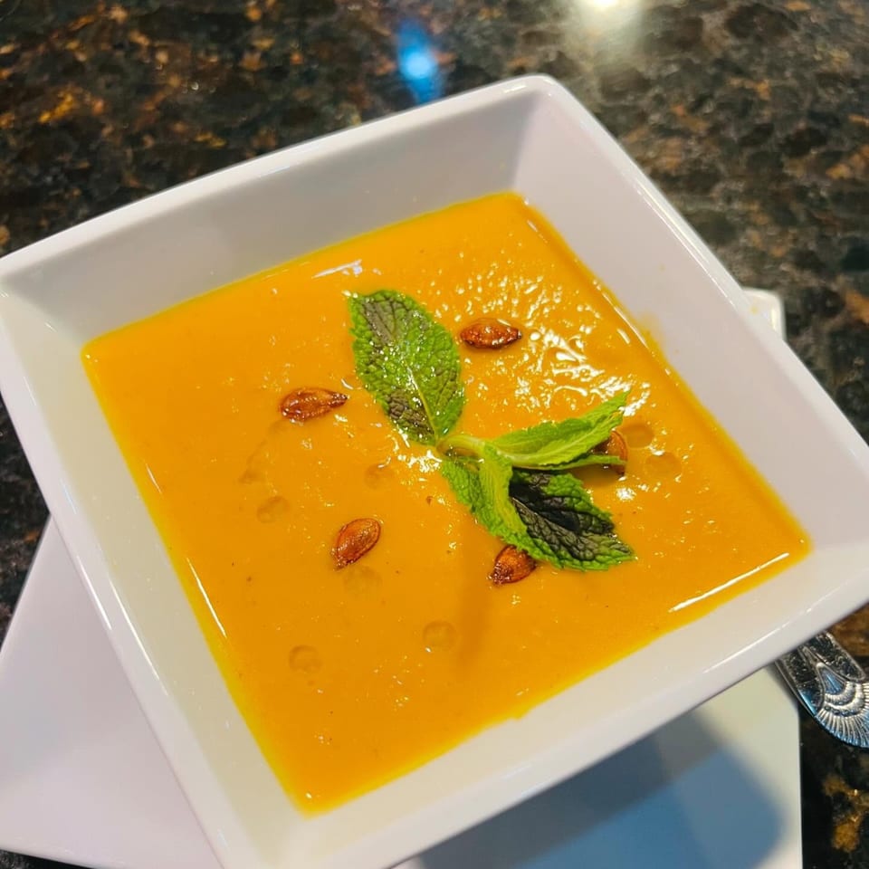 Woondal Restaurant & Grill's vibrant orange Indian soup, garnished with fresh mint and pumpkin seeds.