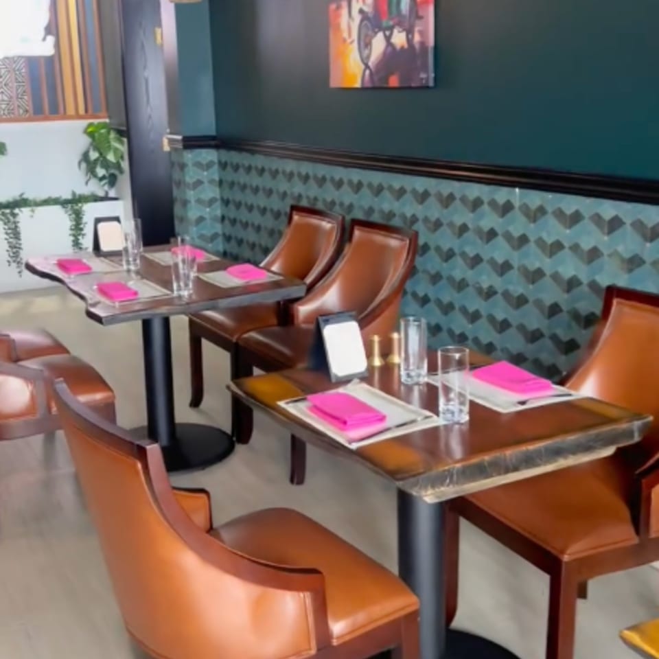 Woondal Restaurant & Grill's dining area with brown leather chairs, wooden tables, and teal patterned walls.